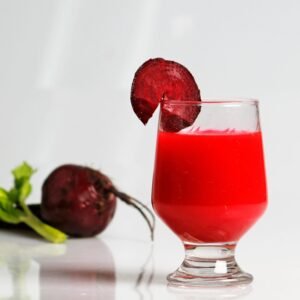 A refreshing glass of beetroot juice garnished with a fresh beet slice on white background.